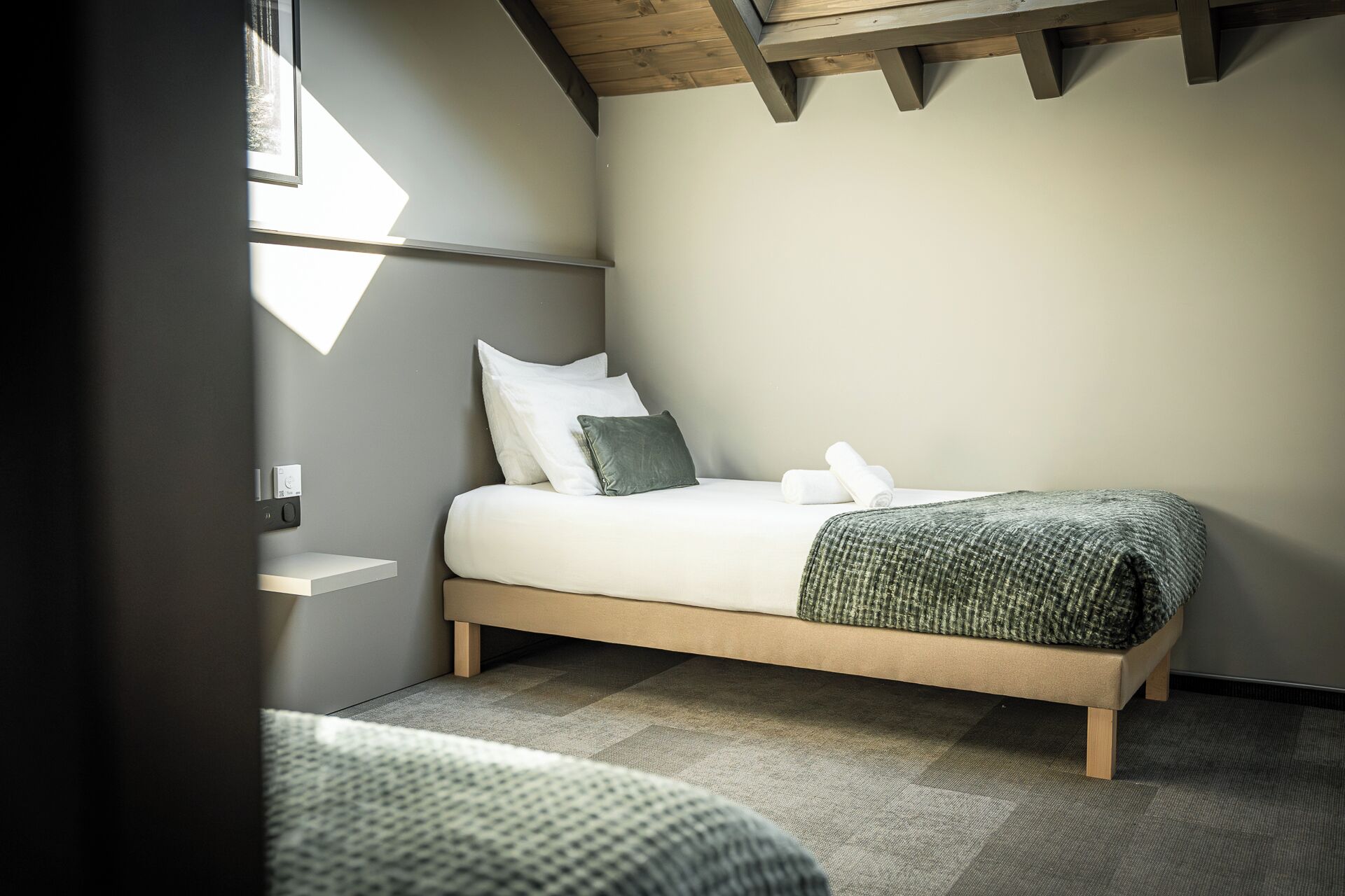 A bedroom with a bed, pillows, a bedside table, and a window.