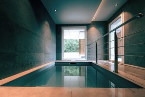 Ein moderner, überdachter Schwimmbereich mit Blick auf Grünflächen.