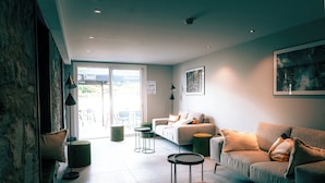 A modern living room with a sofa, a coffee table, and a dining area with chairs. - L'Echappée Vosgienne (Gérardmer)