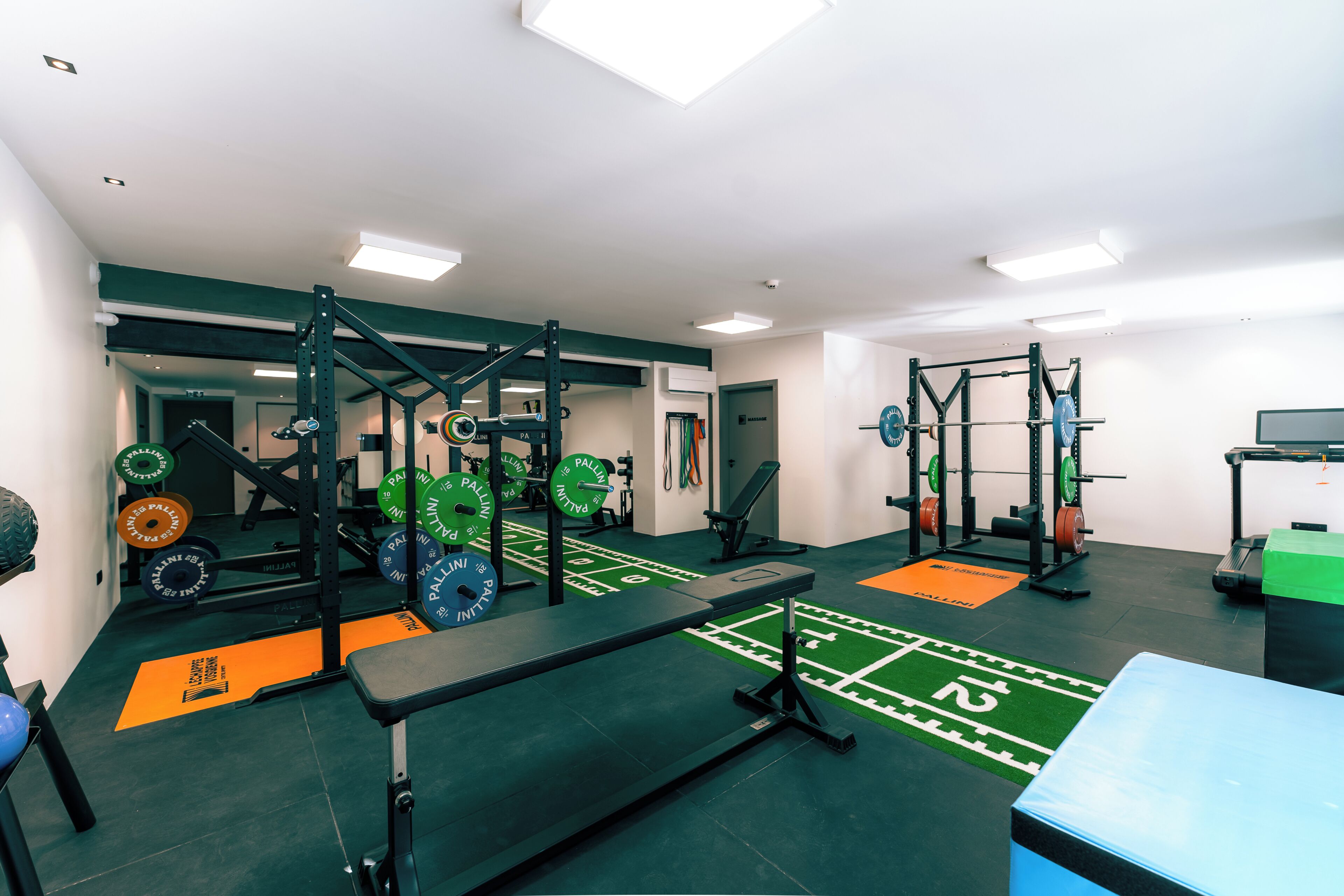 A gym with weightlifting equipment, benches, and a green turf area.