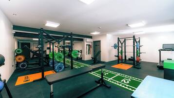A gym with weightlifting equipment, benches, and a green turf area.