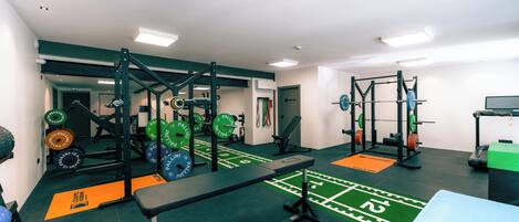 A gym with weightlifting equipment, benches, and a green turf area.