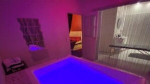 Ein Zimmer mit einer großen Badewanne, einem Vorhangfenster und einer Tür, die auf einen Balkon führt.