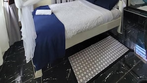 Un lit à baldaquin blanc, avec une literie bleue et un tapis à motifs.