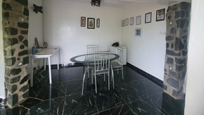 Un coin repas avec une table ronde et des chaises, un mur en pierre servant d’élément décoratif et des tableaux encadrés accrochés au mur.