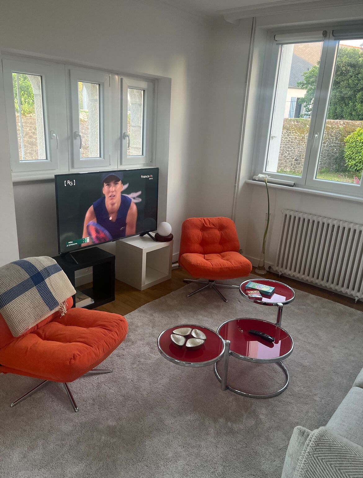 Ein modernes Wohnzimmer mit Fernseher, orangefarbenen Sesseln und einem Couchtisch.