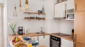 A modern kitchen with wooden countertops, a built-in oven, a microwave, and hanging light fixtures.