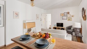 A modern kitchen with a dining area, a sofa, and a TV in the living room.