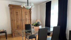 A dining area with a glass table, black chairs, a wooden cabinet, and a flower vase. - Former wine château (Winningen)
