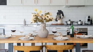 Una mesa de comedor dispuesta con platos, copas de vino y un florero.