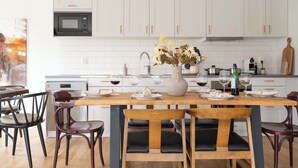 Una cocina moderna con armarios blancos, un microondas y una mesa de comedor preparada para cuatro personas.
