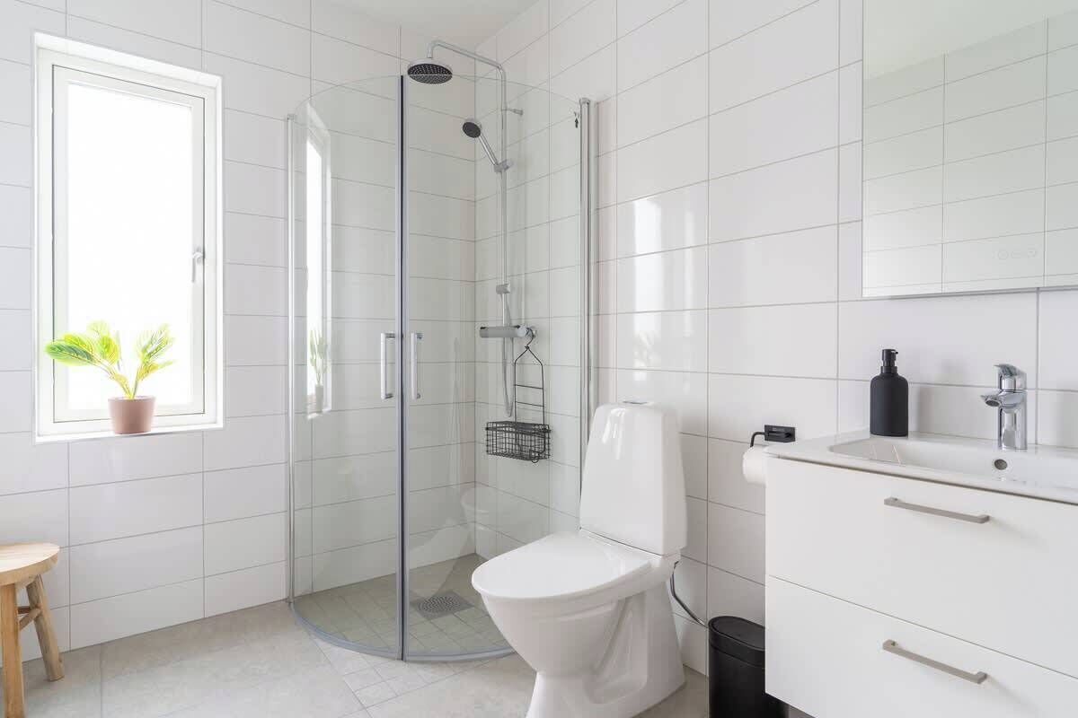 A modern bathroom with a glass shower enclosure, a toilet, and a vanity with a mirror.