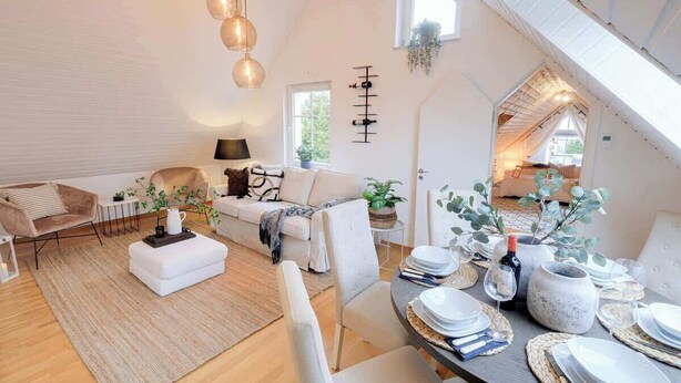 A spacious living area with a high ceiling, a dining table set for a meal, and a cozy seating area with a sofa and armchairs. - Fully Equipped Home Close to Malmo Copenhagen (Vellinge)