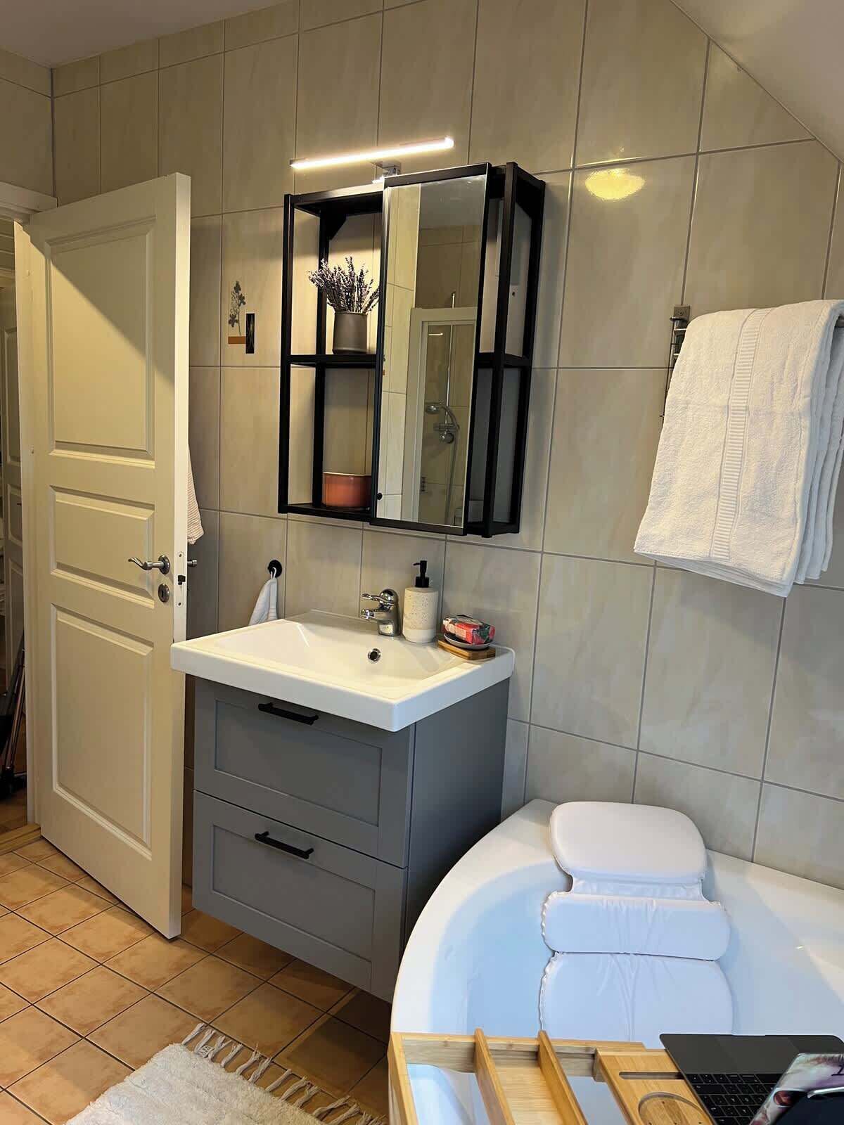 Ein Badezimmer mit weißem Waschbecken, einem Spiegel, einer Toilette und einer Badewanne.