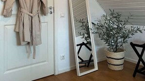 A room with a white door, a beige robe hanging on the door, a large mirror leaning against the wall, and a potted plant. - Fully Equipped Home Close to Malmo Copenhagen (Vellinge)