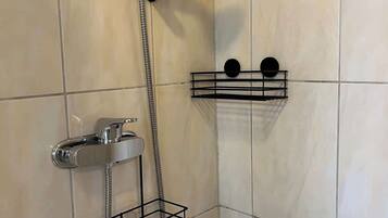 A shower with a handheld showerhead and a wall-mounted faucet, with two black towel racks on the wall.