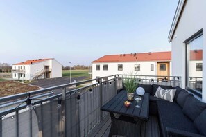 A balcony with a black table, a black sofa, and a potted plant. - Chocolaty Warmth Home 3BR Flat with Cozy Balcony (Båstad)