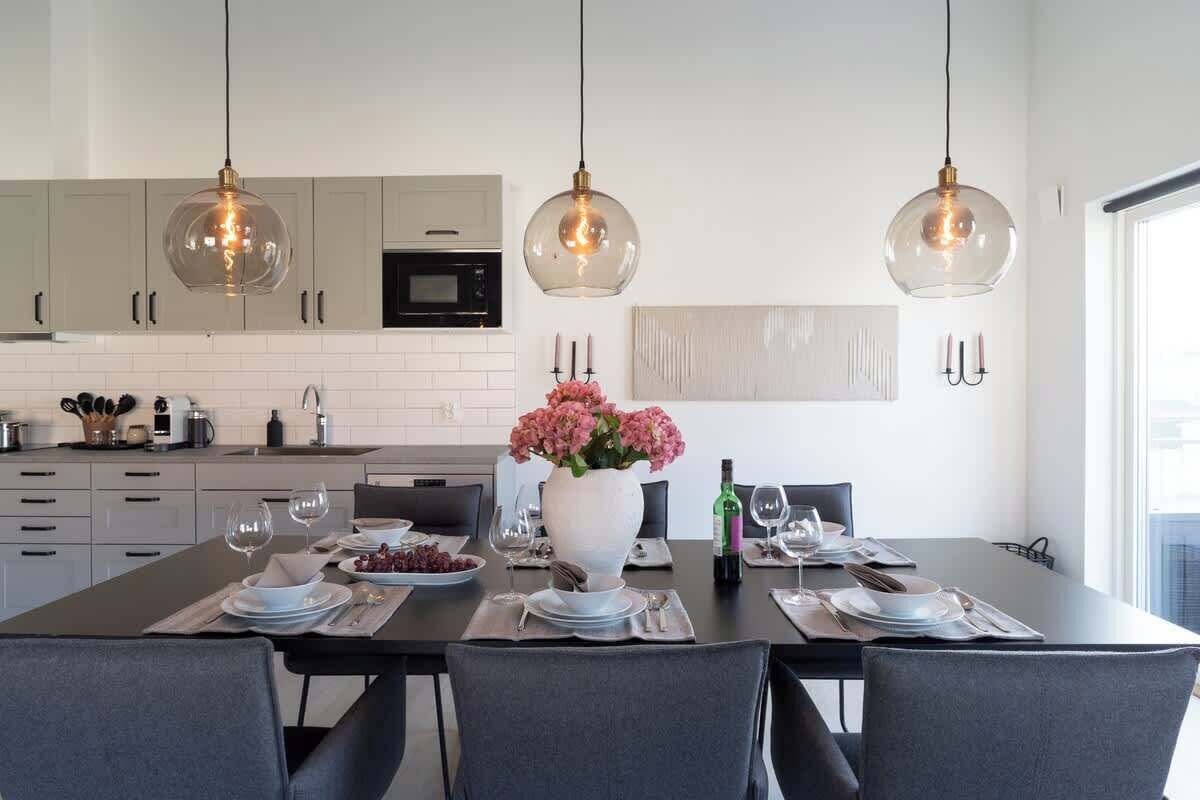 Una cocina moderna con armarios blancos, una isla central con un florero y luminarias colgantes.