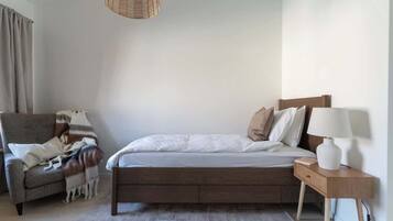 A bedroom with a bed, a nightstand, a lamp, a chair, and a hanging light fixture.