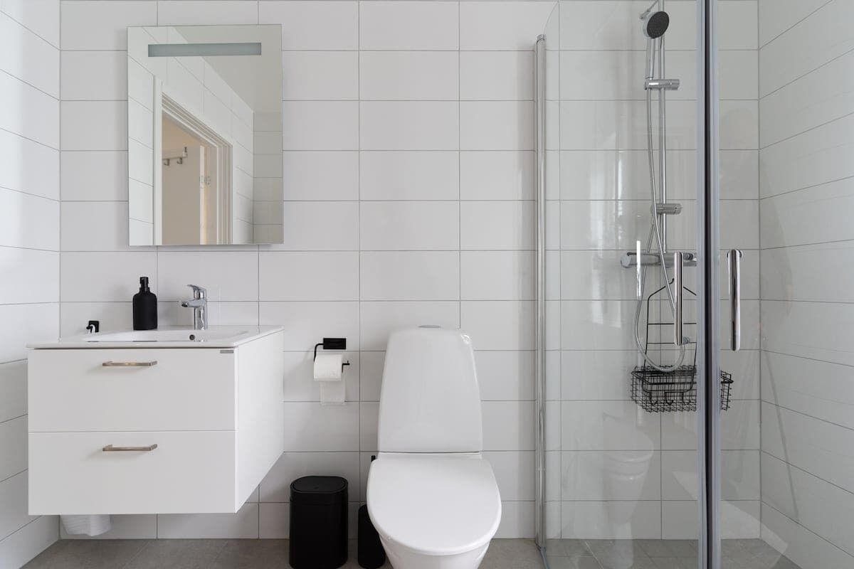 A modern bathroom with a white sink, toilet, and shower.