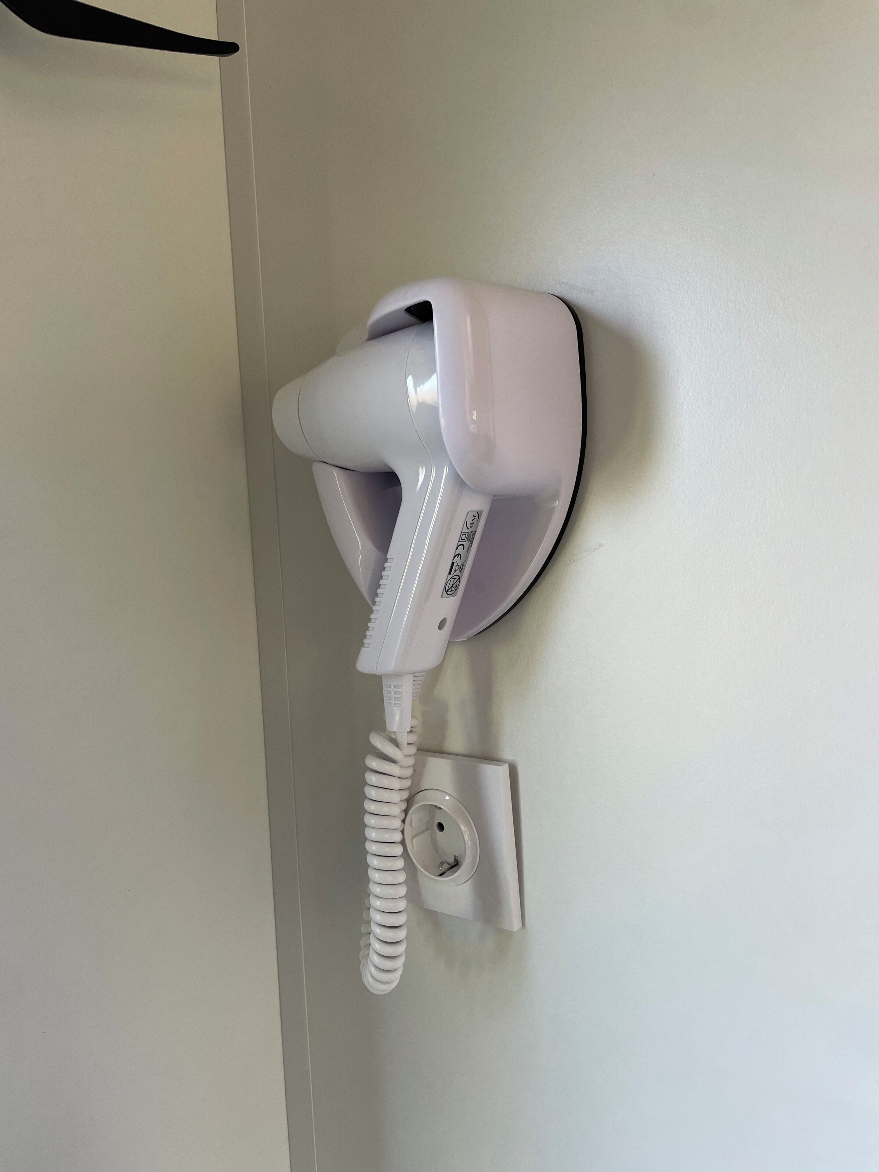 Een witte telefoon bevestigd aan een muur, met een opgerolde snoer.