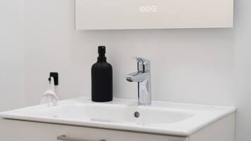 Un bany modern amb un lavabo blanc, una ampolla negra i un aixeta cromada.