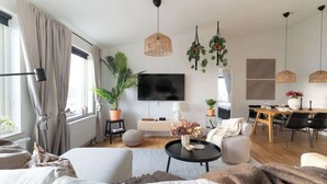 A modern living room with a sofa, coffee table, and dining area. - Spacious Home with Workspace and Cozy Balcony (Båstad)