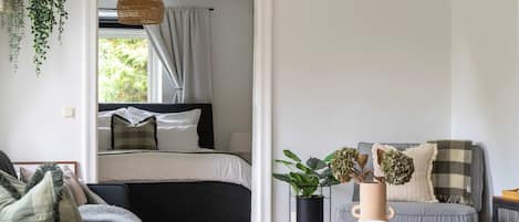 A modern bedroom with a bed, bedside table, and a hanging plant.