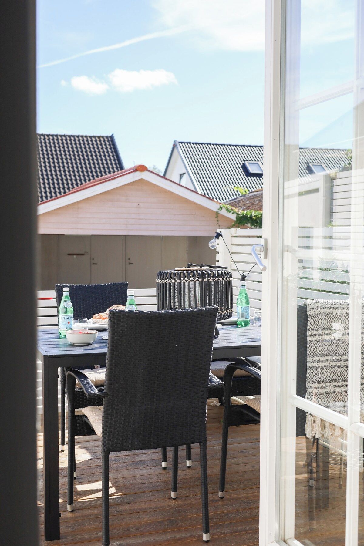 Een terras met een tafel, stoelen en een fles Pellegrino water.