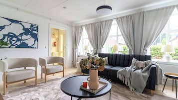 A modern living room with a sofa, two armchairs, a coffee table, and a large abstract painting on the wall.