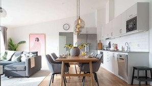 Una cocina moderna con armarios blancos, una mesa de comedor de madera y una lámpara colgante.