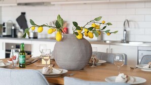 Una mesa de comedor con un jarrón de limones, una botella de vino y platos preparados para una comida.