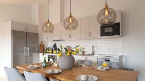 Una cocina moderna con una mesa de comedor de madera, sillas grises y lámparas colgantes.