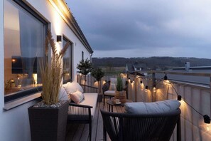 A balcony with wicker furniture, a potted plant, and string lights. - Youthful 3BR Flat w Balcony and Hobby Game Board (Båstad)