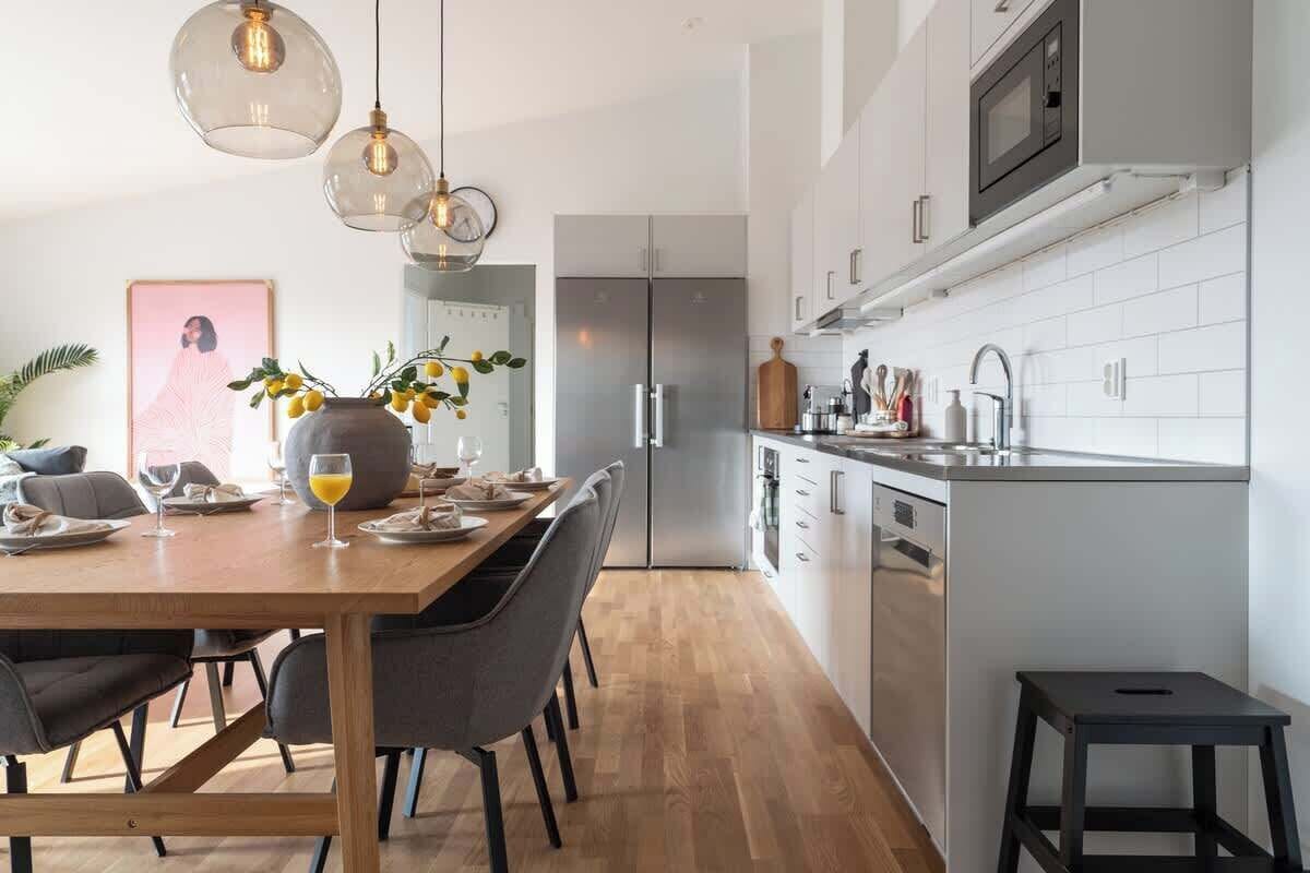 Una cocina moderna con comedor, electrodomésticos de acero inoxidable e iluminación colgante.