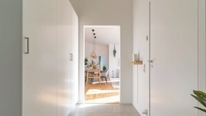 Un pasillo con piso de madera que conduce a un comedor con mesa y sillas.