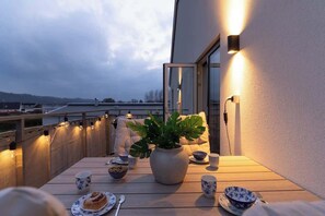A balcony with a table set for tea, a potted plant, and a view of the cityscape. - Modern Beachy Home with Terrace Charm First Floor (Båstad)