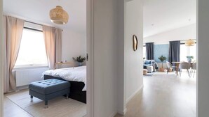 A modern bedroom with a bed, bedside table, and a hanging light fixture.