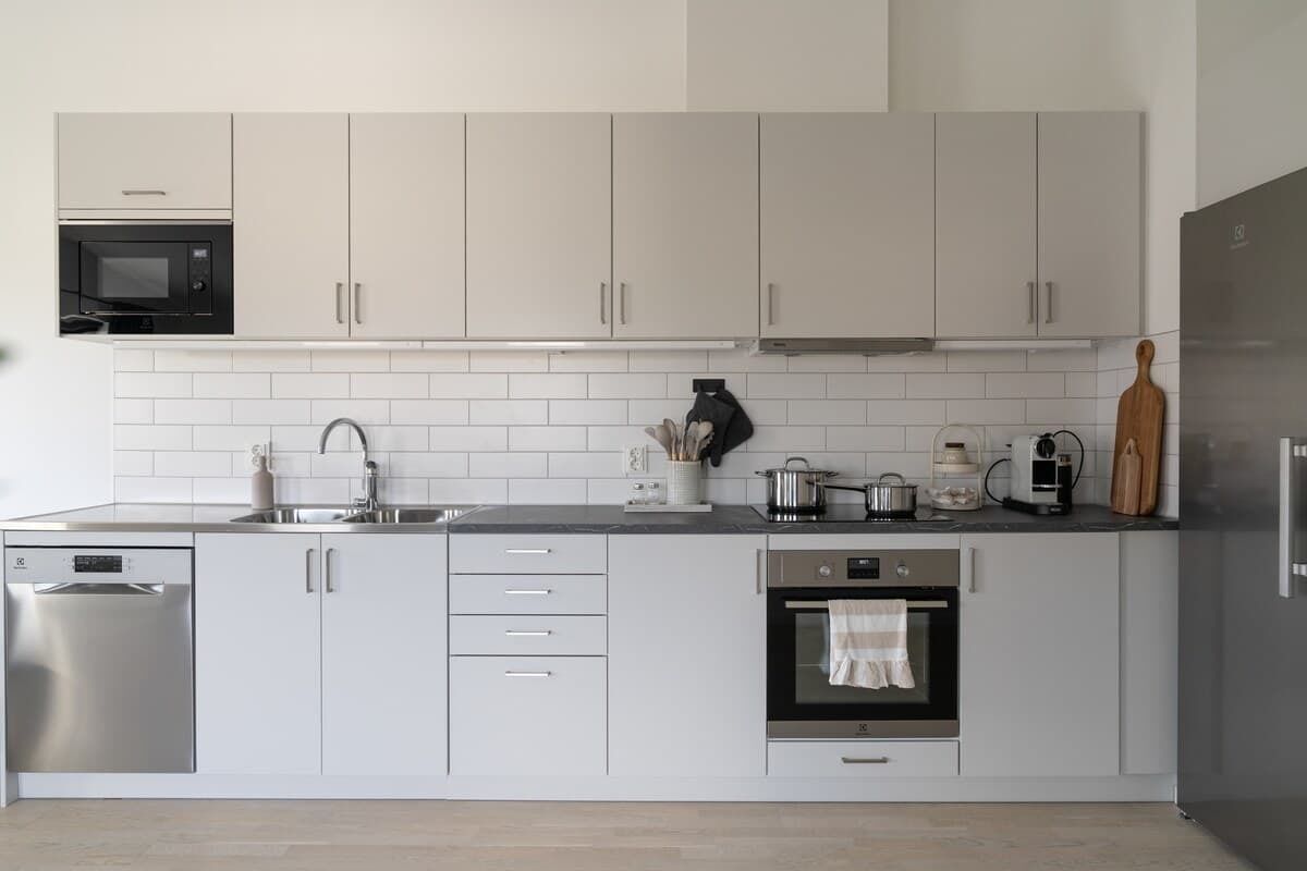 A modern kitchen with white cabinets, a microwave, a coffee maker, and a dishwasher.