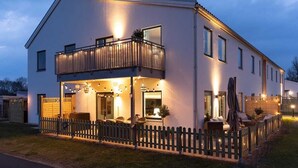 A two-story house with a balcony, a covered patio, and a fenced yard.