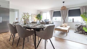 A modern dining area with a round table set for four, surrounded by grey upholstered chairs.