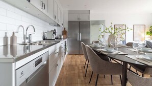 A modern kitchen with white cabinets, stainless steel appliances, and a dining area with a wooden table set for four.