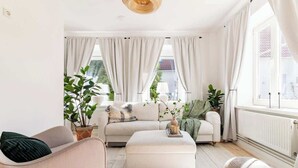 A cozy living room with a sofa, ottoman, and potted plants. - Fully Equipped Apartment Close to Malmo Copenhagen (Vellinge)