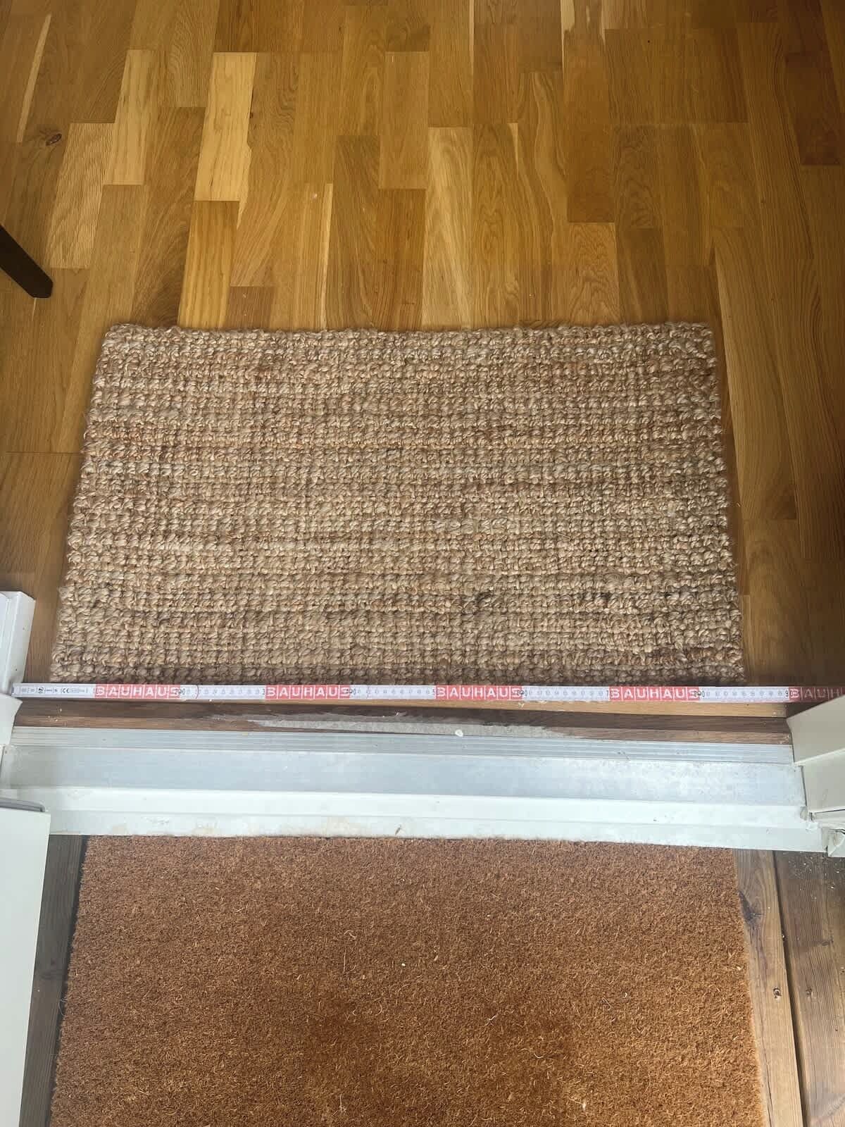 A wooden floor with a textured mat at the entrance.