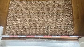 A wooden floor with a textured mat at the entrance.