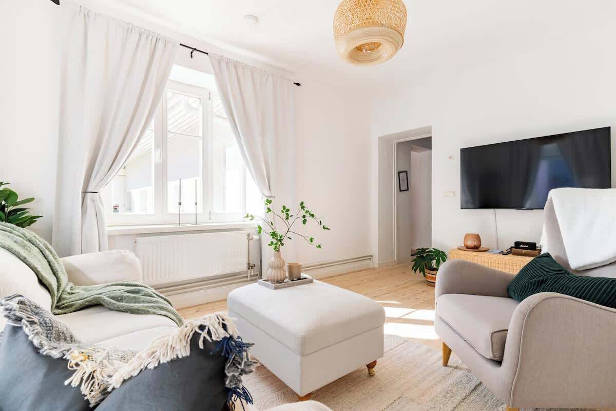 Ein modernes Wohnzimmer mit einer Couch, einem Hocker und einem flachbildfernseher an der Wand.