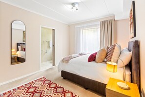 Een hotelkamer met een bed, een bedlampje en een kamerbreed tapijt.