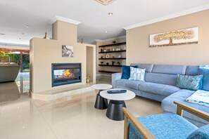 Een moderne woonkamer met een open haard, een zithoek en een salontafel.