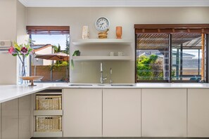 Een keuken met een inbouwspoelbak, een klok en een raam met uitzicht op buiten.