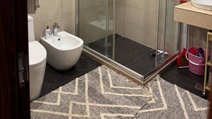 A modern bathroom with a glass-enclosed shower, a white sink, and a bidet.